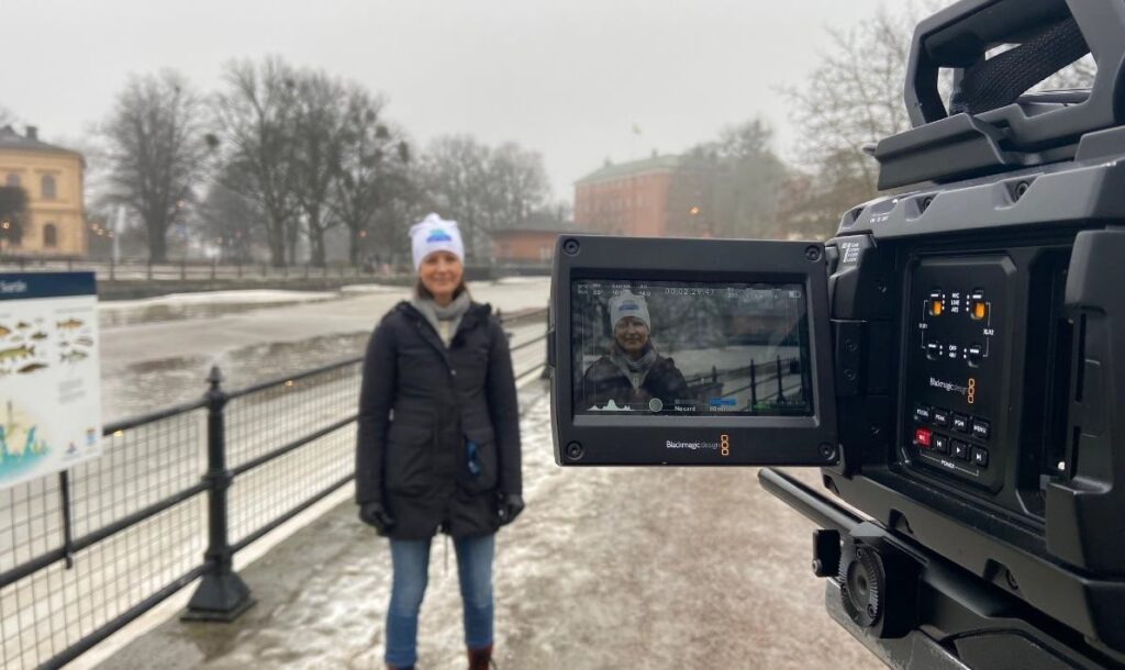 En person står framför en kamera med faunapassagen vid Turbinbron i Västerås bakom sig.